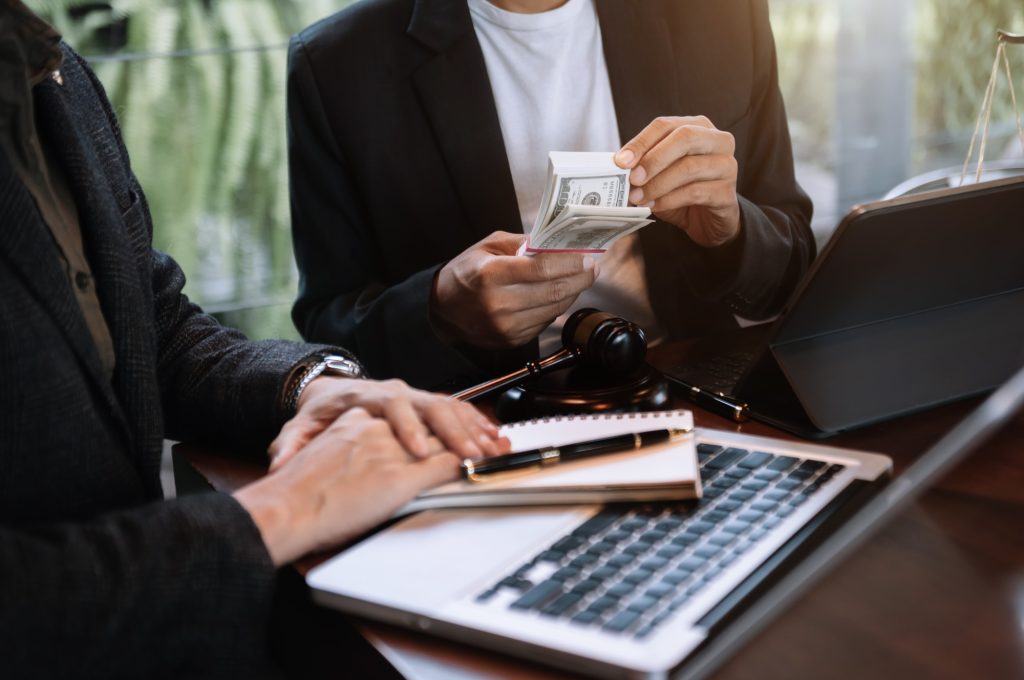 Businessman giving bribe money in the envelope to partner in a corruption scam in office.